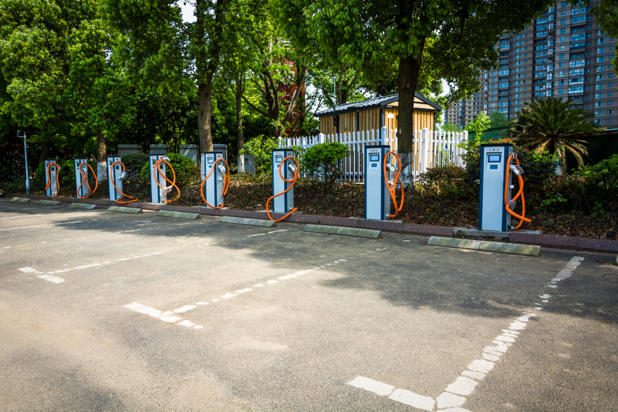 Waarom elektrisch rijden in 2026 een zakelijke prestatiekeuze is Afbeelding: Rij elektrische laadpalen op een parkeerterrein met lege parkeervakken