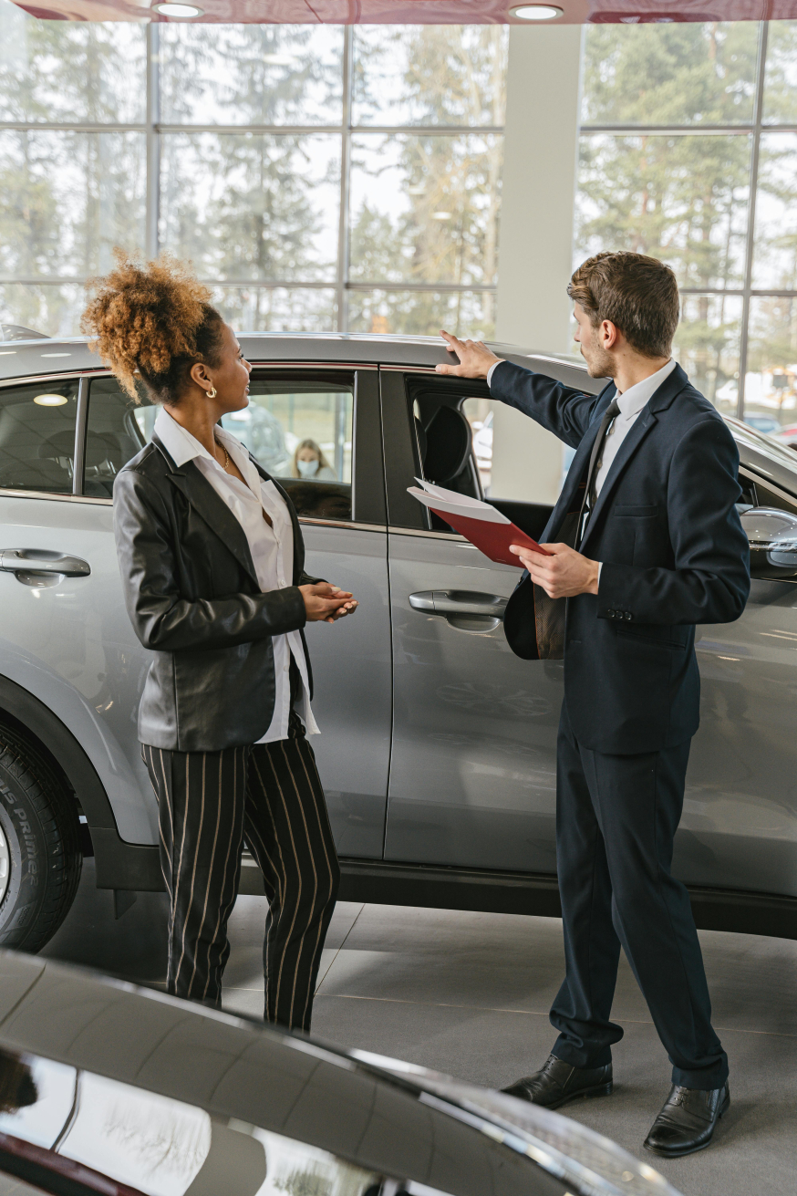 Waarom elektrisch rijden in 2026 een zakelijke prestatiekeuze is Afbeelding: Zakelijke klant en adviseur bespreken een elektrische auto in een showroom