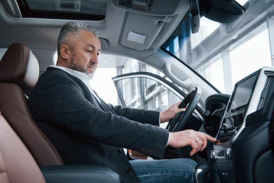 Waarom elektrisch rijden in 2026 een zakelijke prestatiekeuze is Afbeelding: Zakelijke rijder zit in een auto-interieur en bedient het scherm op het dashboard van zijn elektrische auto